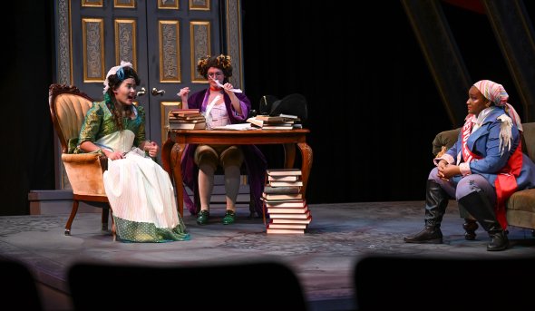 Three women act on a stage.