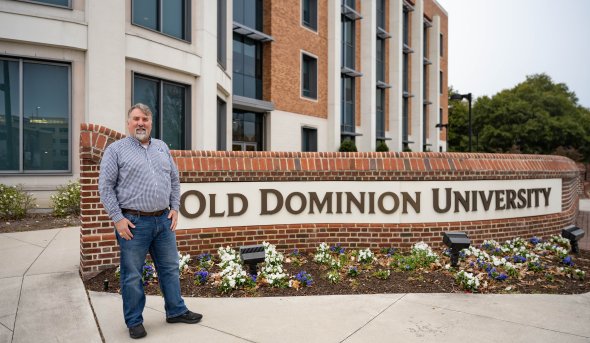 ODU alumnus Rob Wilber in front of a sign that reads Old Dominion University 