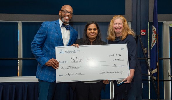 A student holds a big check she received as winner of the Kaufman Award.