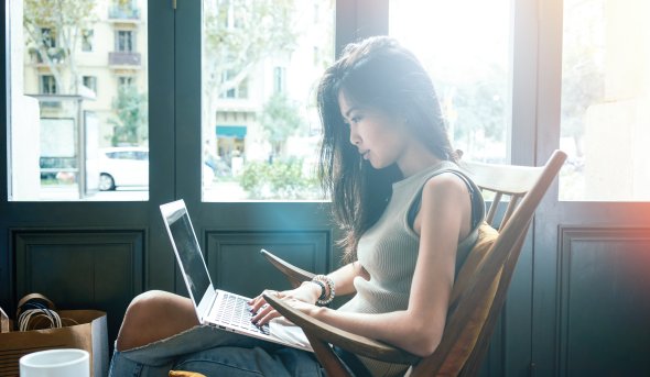 women sitting on couch typing on a laptop