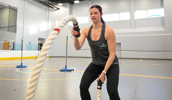 A woman exercises with large ropes.