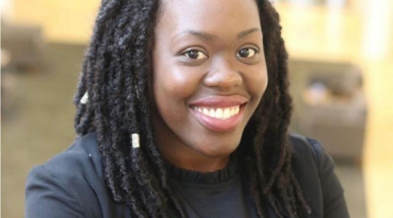 Young woman with locs and a bright smile.