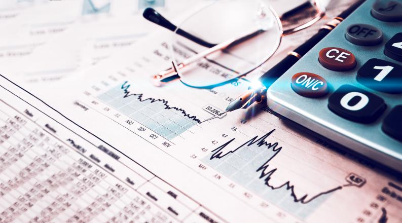 a calculator is laying on top of papers depicting charts and bar graphs