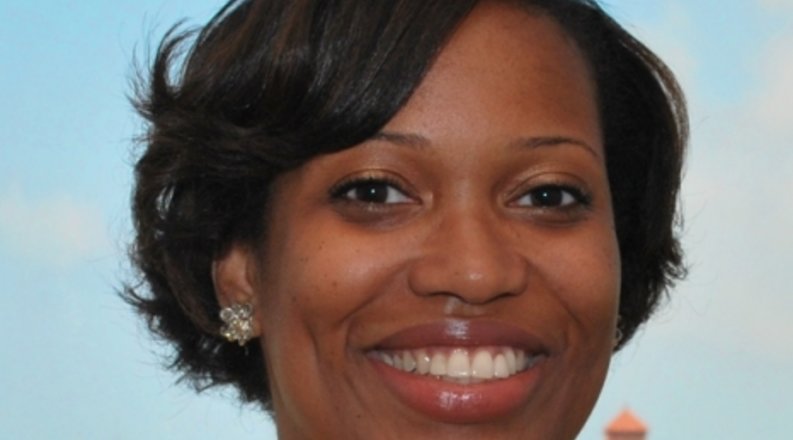 A woman with a yellow blouse smiling for the camera.