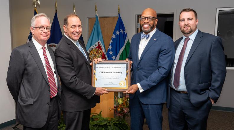 four men in blue suits accept an award
