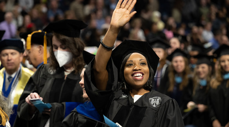 an odu doctoral student waves to the crowd with a diploma in her hand