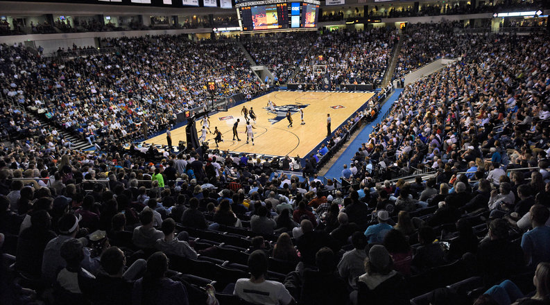 An arena full of fans watches a basketball game.