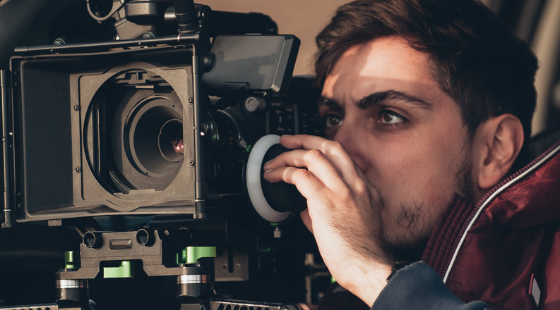 Student looks through film camera. 