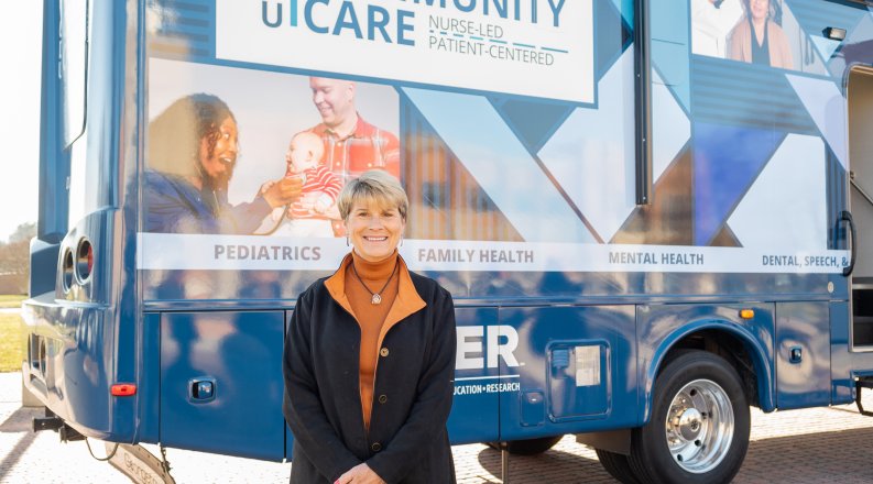A smiling woman poses in front of a blue van.