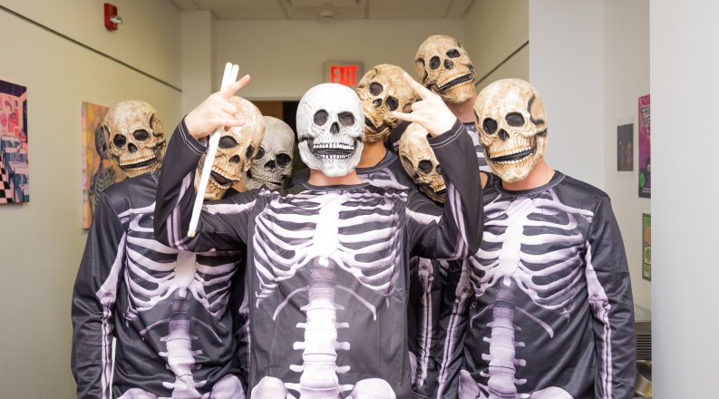 A group of students dressed in skeleton costumes pose for a photo.