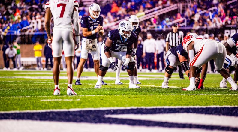 A group of football players stand on a field during a game. 
