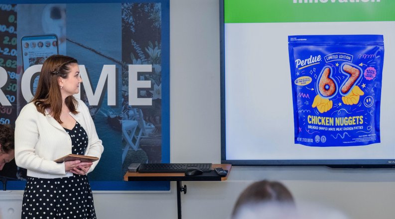 Student stands in front of class looking at Perdue produce