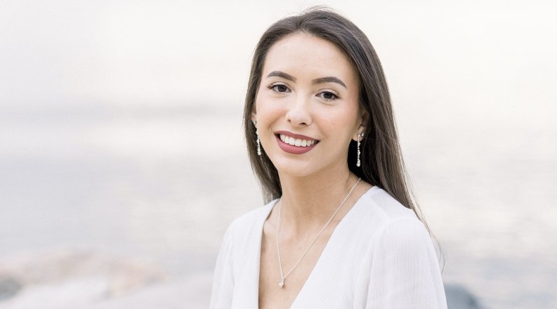 A woman sits on a rock at the beach