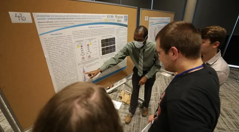 student points at research poster