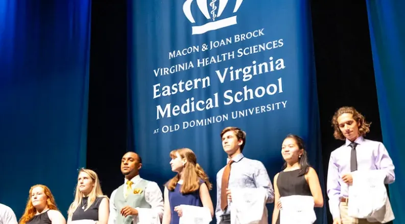 students on a stage with white coats.