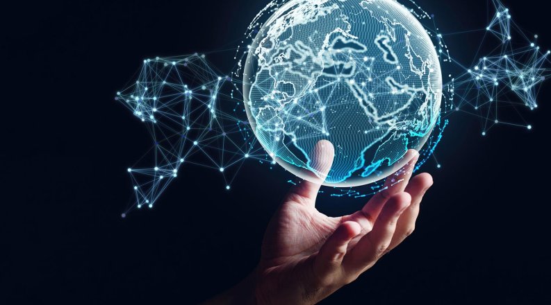 A human hand appears to hold up a holographic globe of the world.