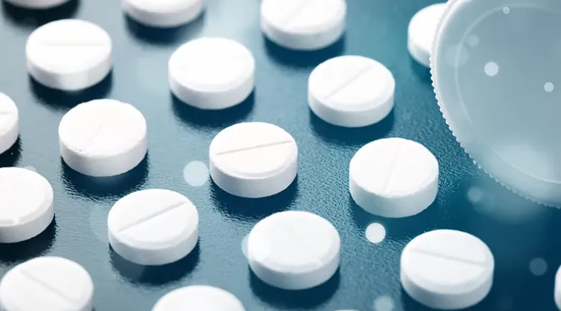 A close-up of white pills arranged in straight lines on a da
