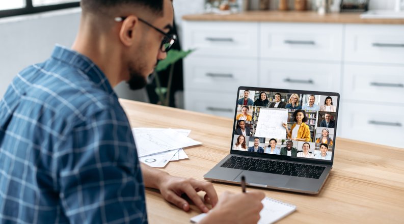 A person in front of a laptop engaging with a group of people online