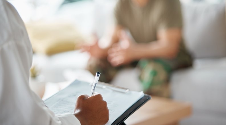 Counselor taking notes on a clipboard with a service member. 