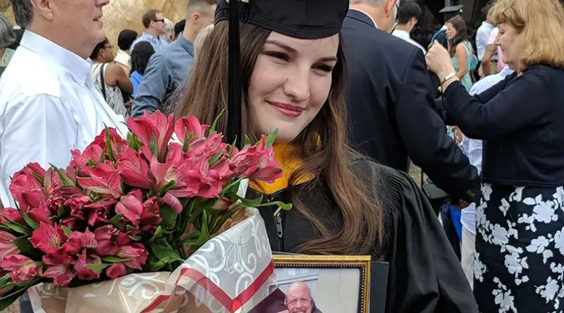 Ciara Jenkins on graduation day holding a photo of her dad.