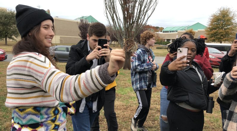 a woman holds a bird while others take photos 