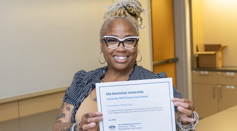 Ebony Clark poses with a certificate showing she is the 2025 Staff Dream Fund award recipient.