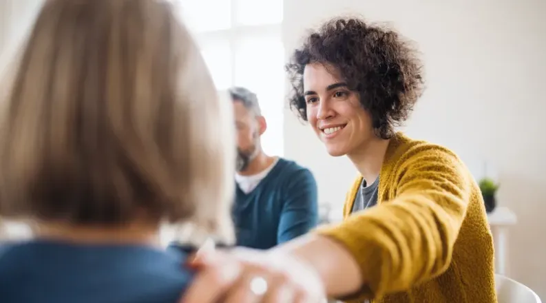 Woman in yellow sweater putting hand on shoulder