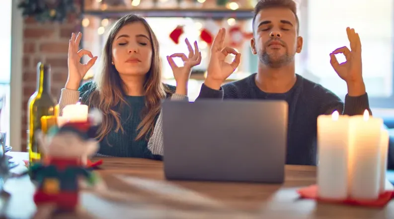 Man and woman meditating in front of an open laptop during t