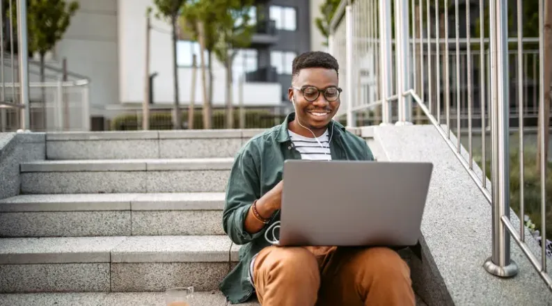 Man sitting on stairs using a laptop