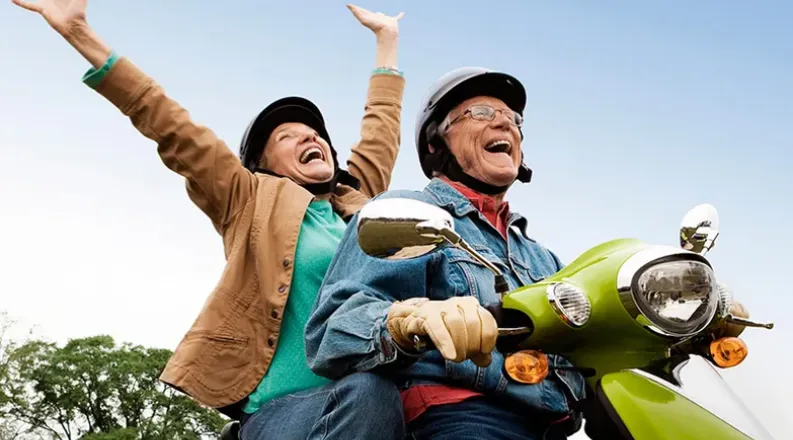 Two older people are riding a lime green motorized scooter a