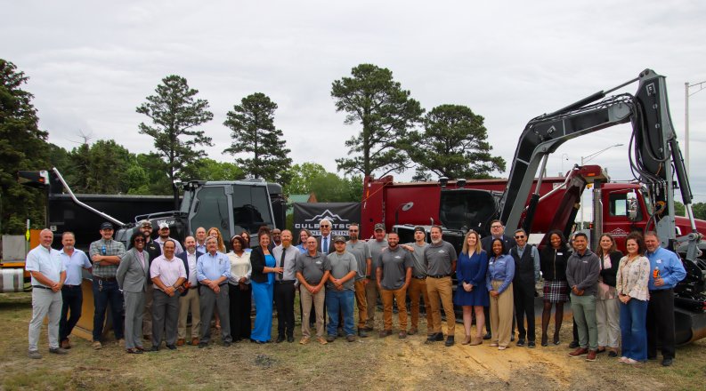 A group of people standing in front of construction equipment.