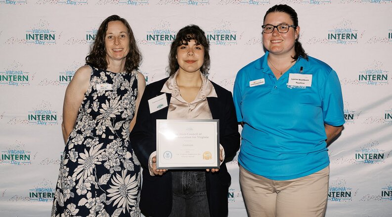 3 students standing middle one holds award