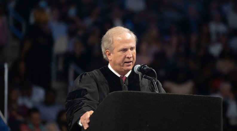 Man speaking behind a podium at a commencement ceremony