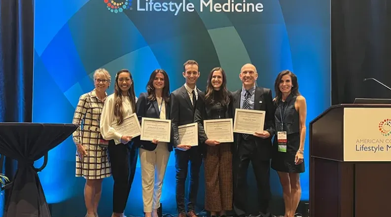 Stephen Manga stands on a stage with other award recipients