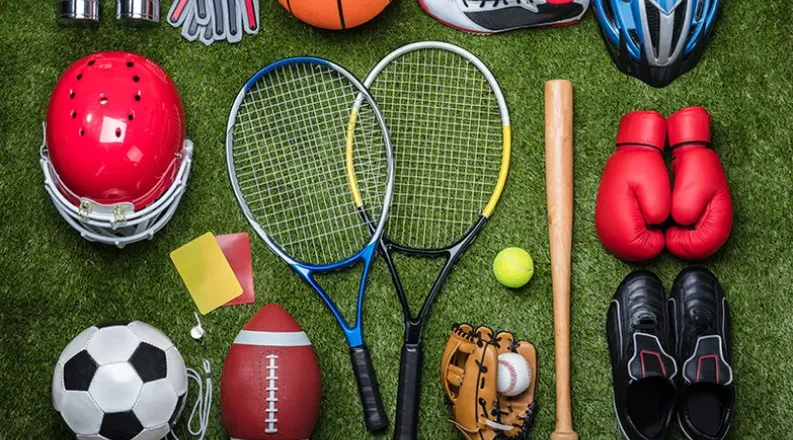 Various sports equipment lays on a green grass background. I