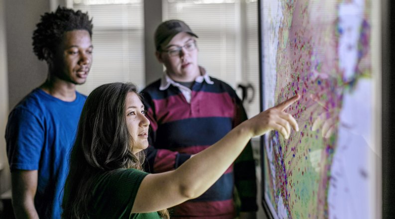 3maritime students work in front of map