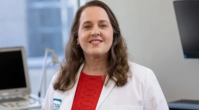 Dr. Morales has long wavy brown hair, is wearing a red sweat