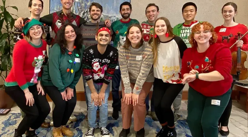 Singing group members in holiday sweaters