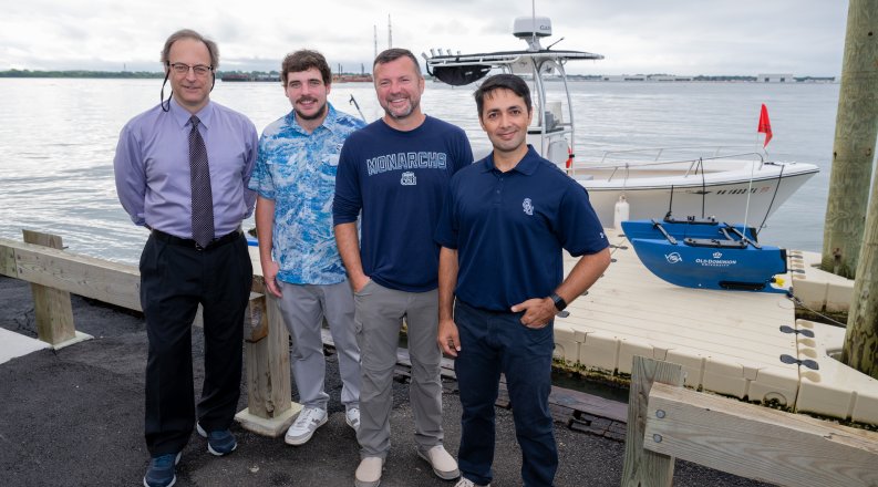 Four men stand in front of boat