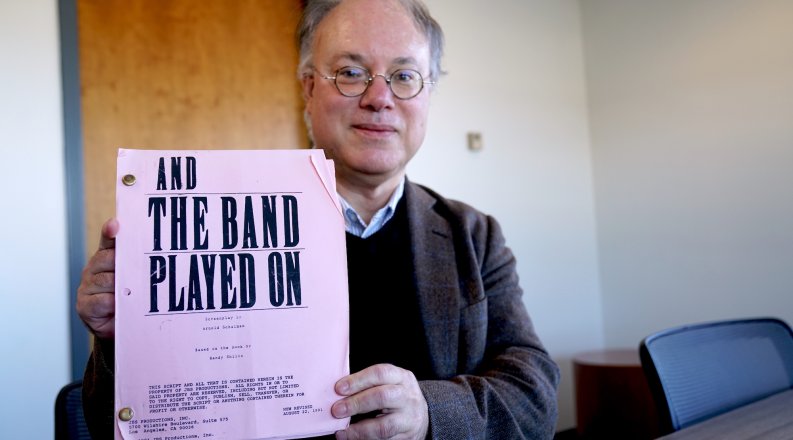 A man holds up a film script. 