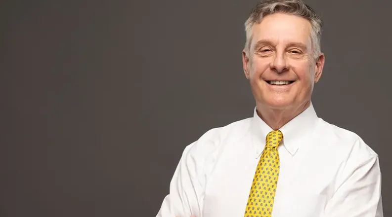 Dr. Pike has short gray hair, is wearing a white dress shirt