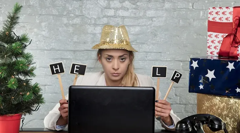 A woman is wearing a festive holiday hat surrounded by wrapp