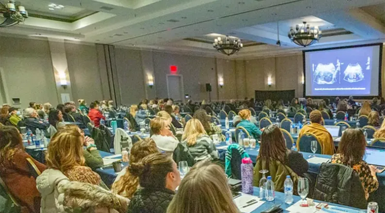 conference room with hundreds of people sitting looking at a