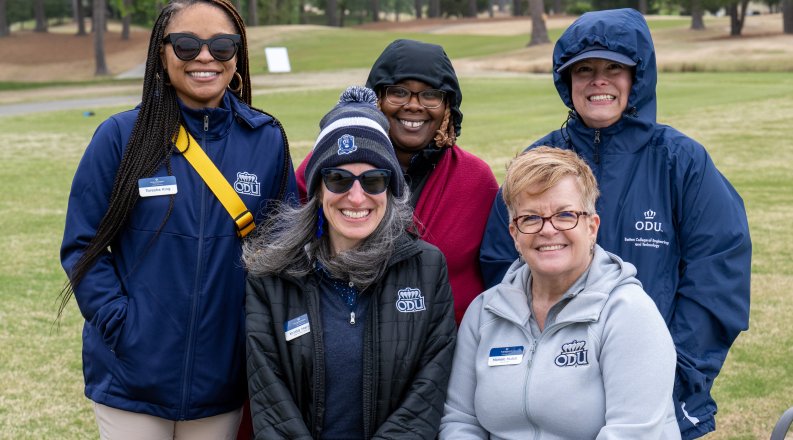 A group of people pose for a photo on a golf course. 