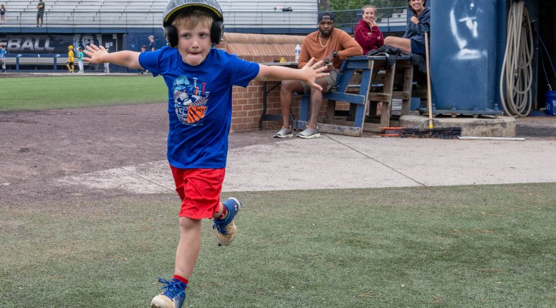 A young baseball player rounds the bases after hitting a home run. 