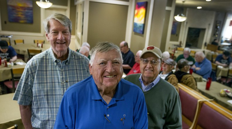 ODU alumni David Willett ’74, Jim Witcher ’75  and Billy Goodson Jr. ’71 stand in a restaurant. 