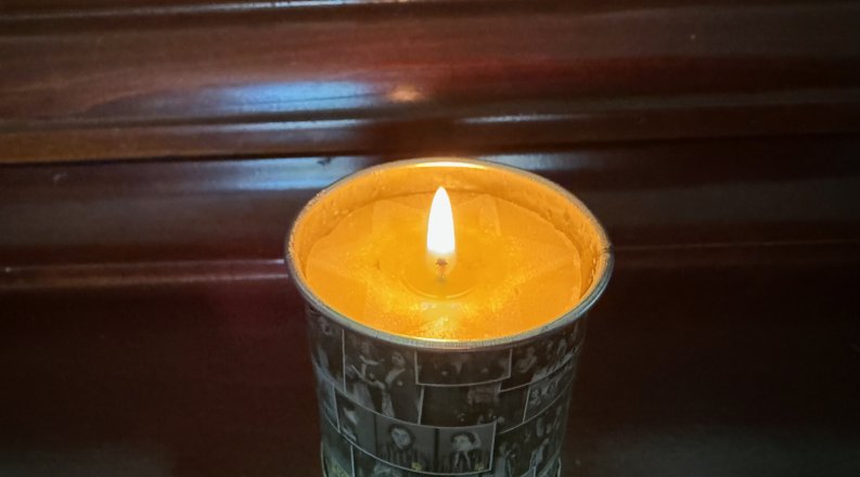 a lit tea light candle on a desk.