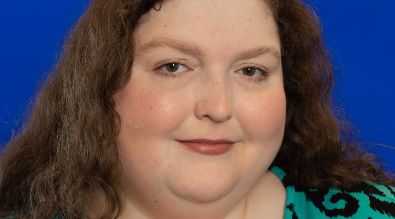 A woman smiles in a green patterned dress.