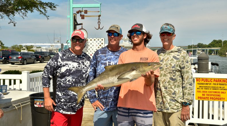 Group of men holding a cobia fish