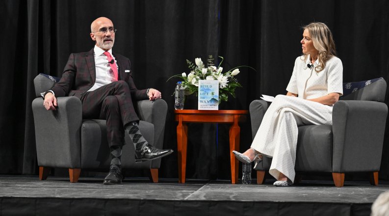 a man and women sit in chairs on stage